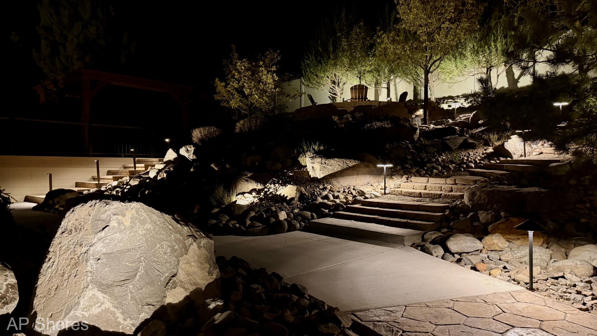 The image depicts a serene outdoor setting, featuring a stone pathway and stairs illuminated by lights at night.